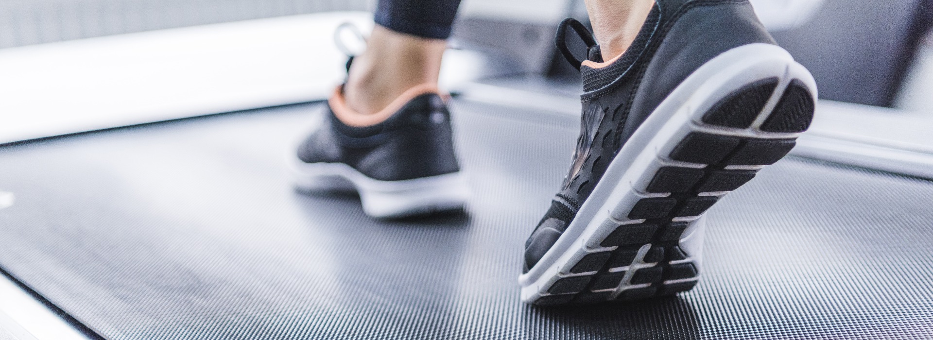 cropped shot of woman in jogging sneakers running on treadmill