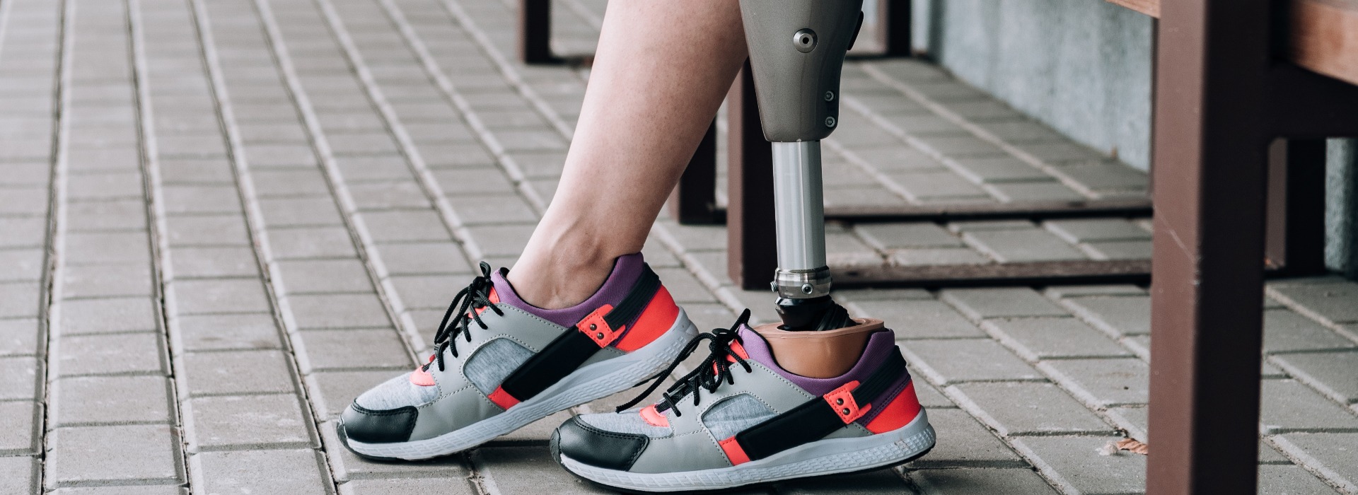 panoramic shot of disabled sportswoman with prosthetic leg on street