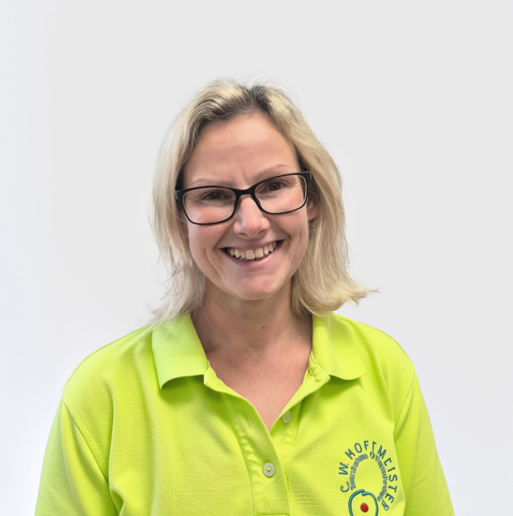 Laechelnde blonde Frau mit Brille im neongruenen Poloshirt mit Firmenlogo